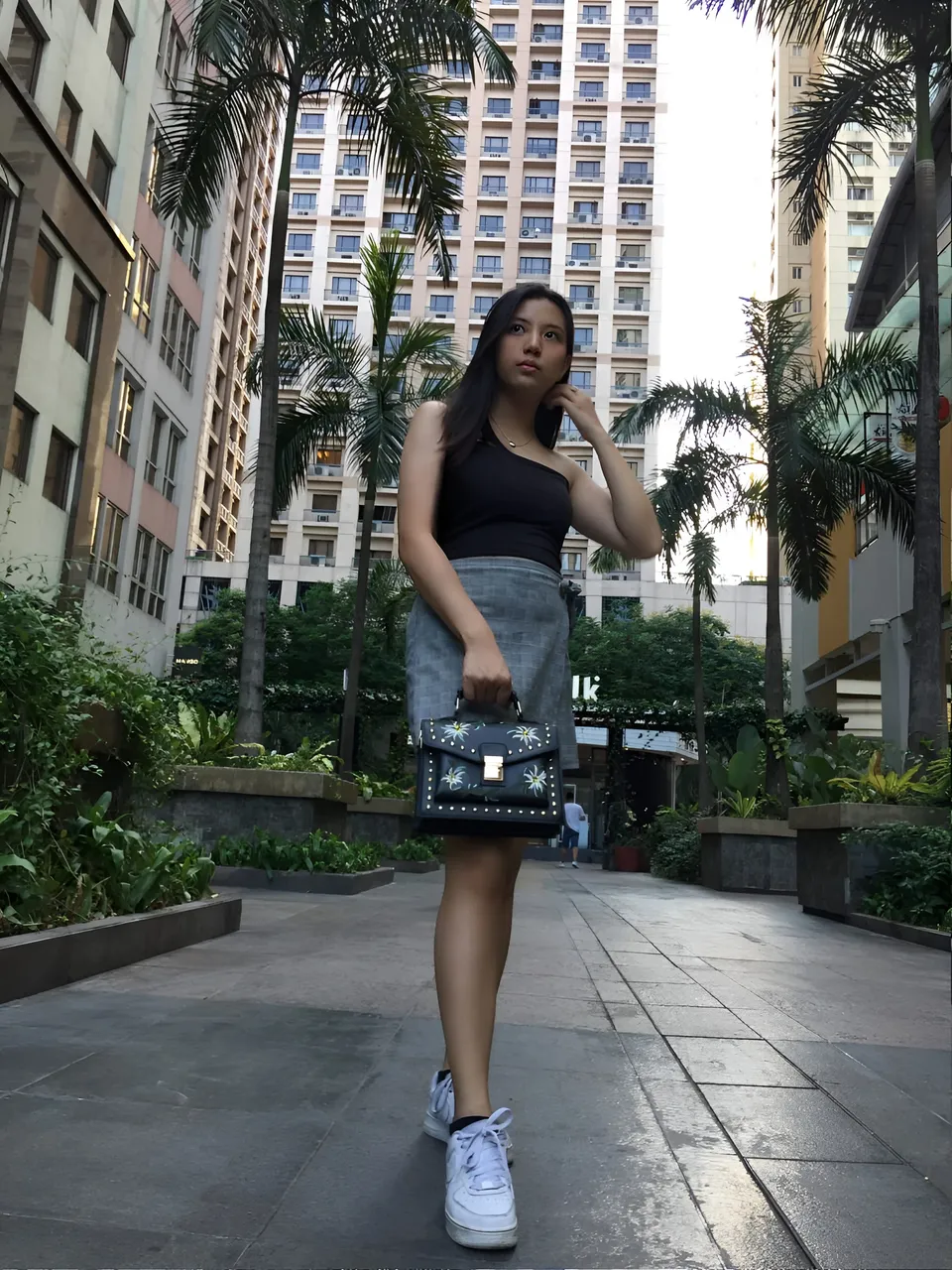 Alekzandra Hart standing on paved walkway holding handbag