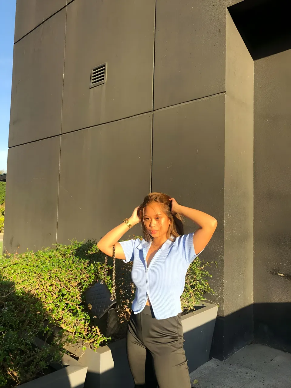 Ally Romano in blue striped shirt standing outdoors near building