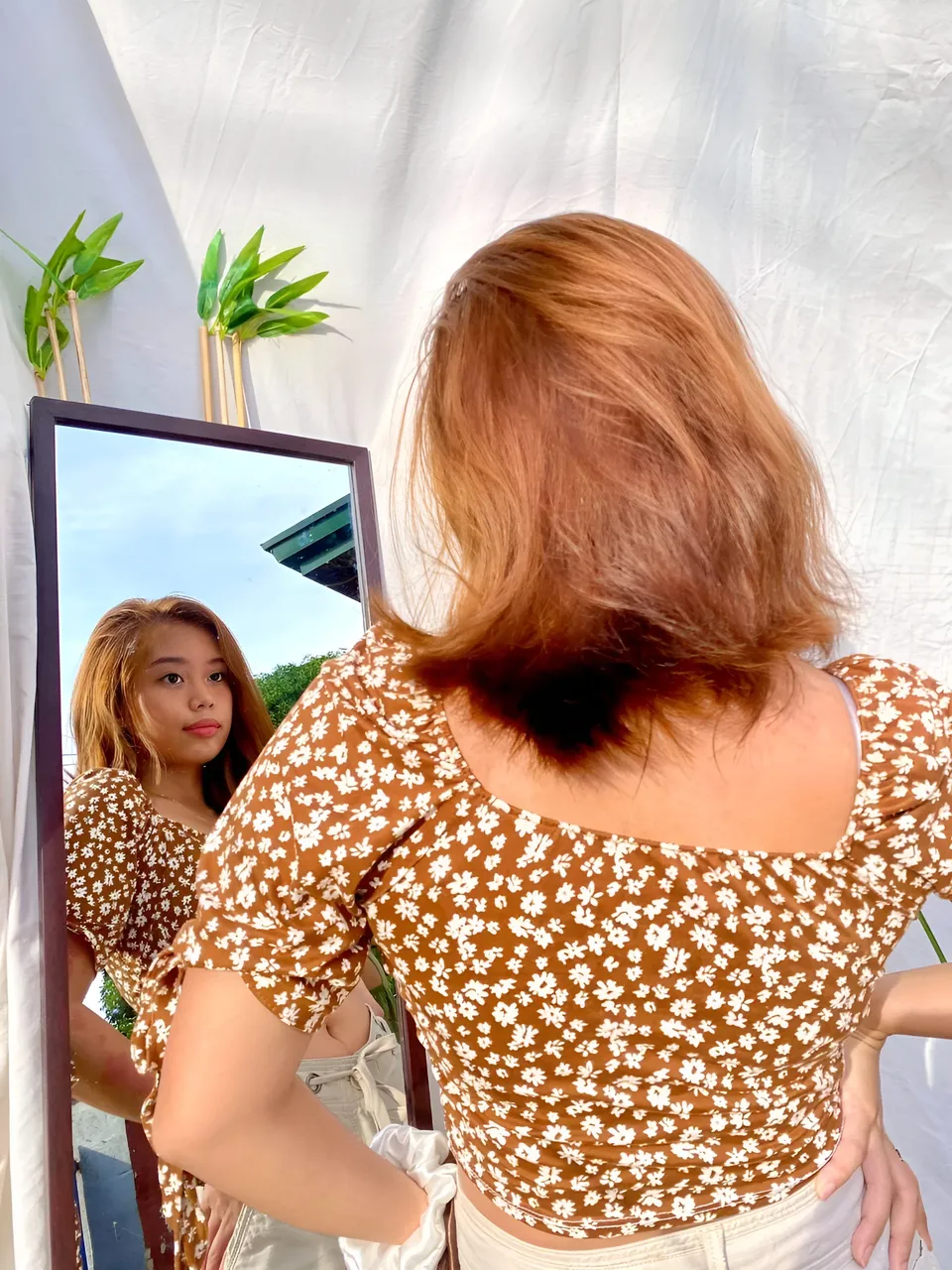Ally Romano in brown floral top views reflection in mirror