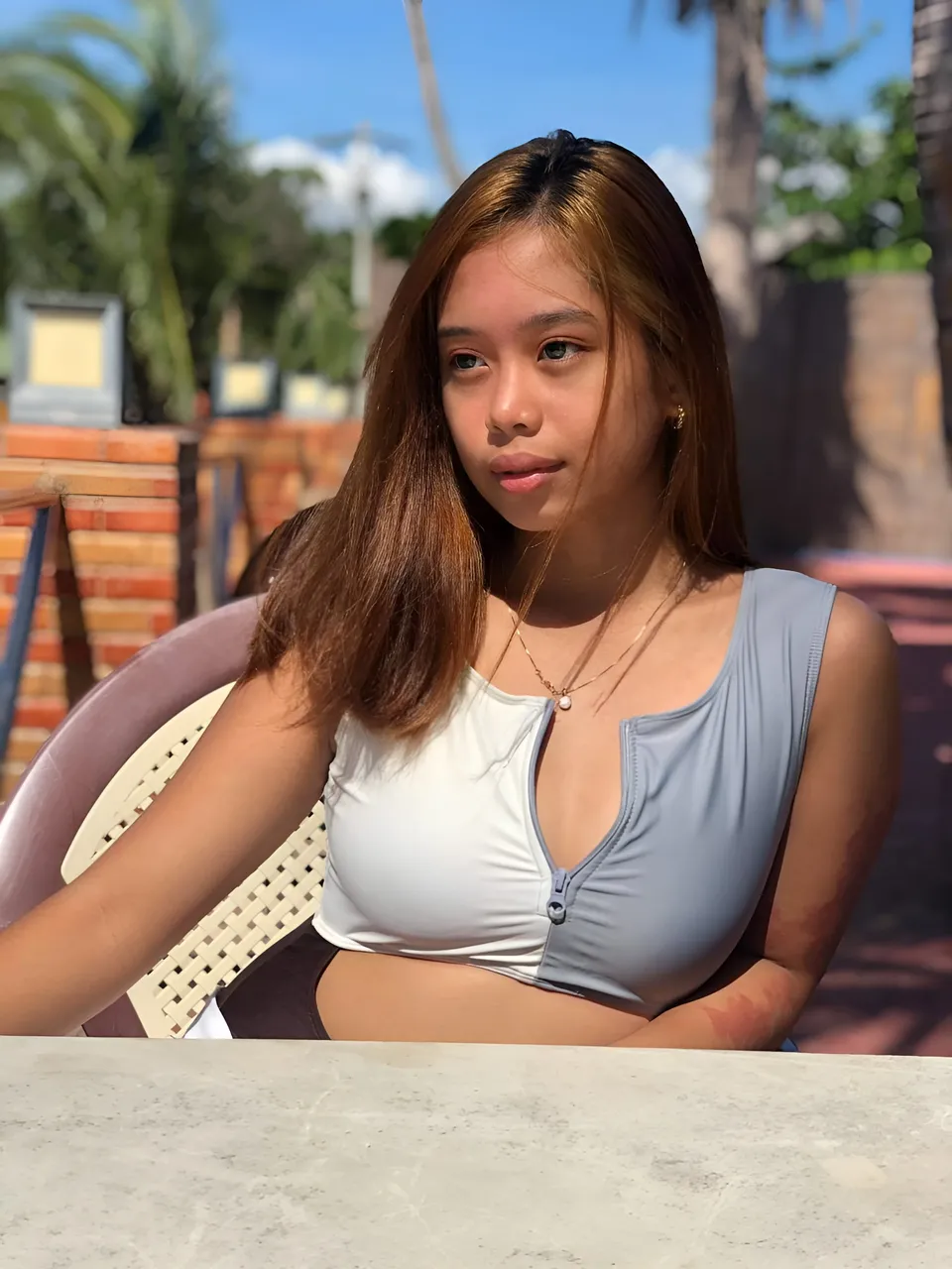 Ally Romano wearing two-toned top seated at outdoor table