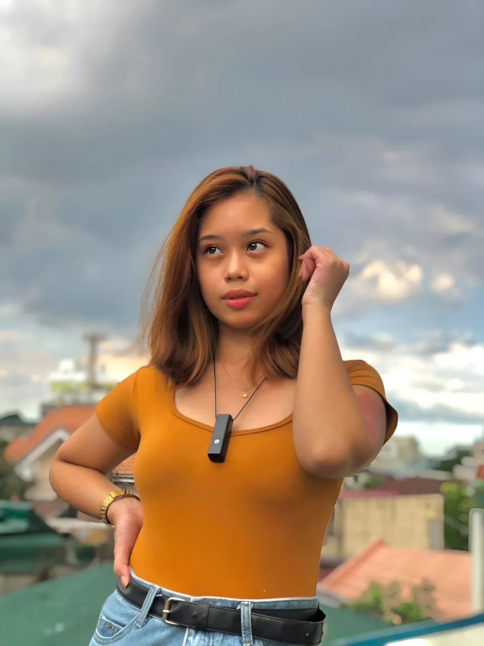Ally Romano in orange top standing outdoors with cloudy sky