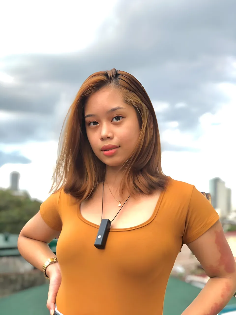 Ally Romano in orange top standing outdoors with cloudy sky