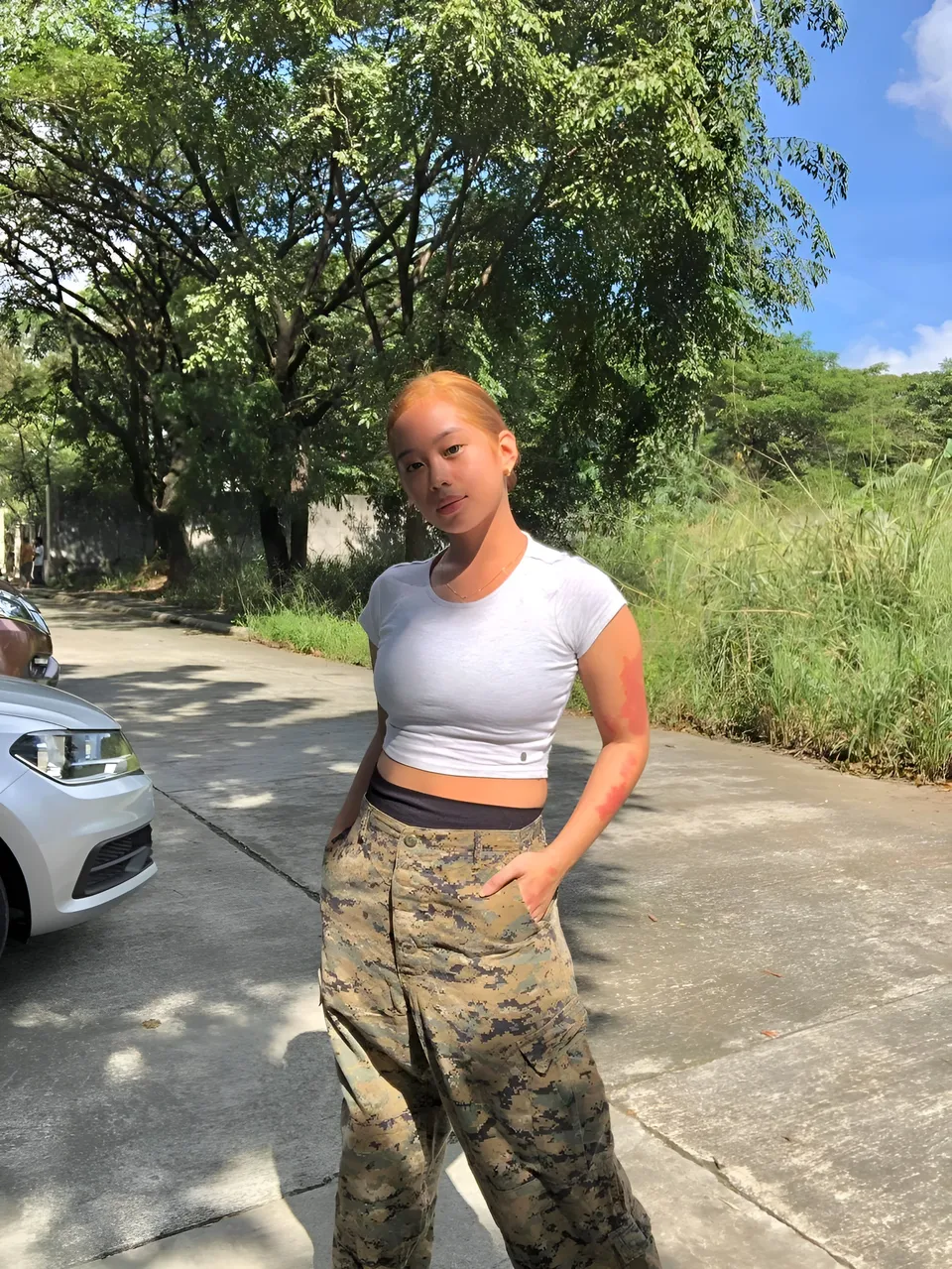 Ally Romano standing outdoors in white crop top and camouflage pants