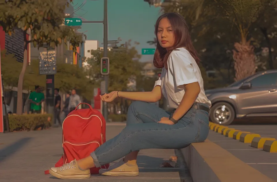 Andrea Jana Ladores sits on curb with red backpack beside her