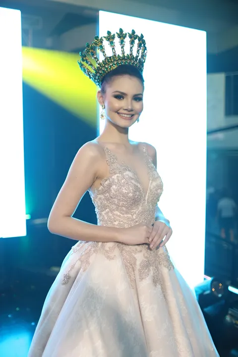 Angela Maria Robson in beaded gown and crown poses for photo