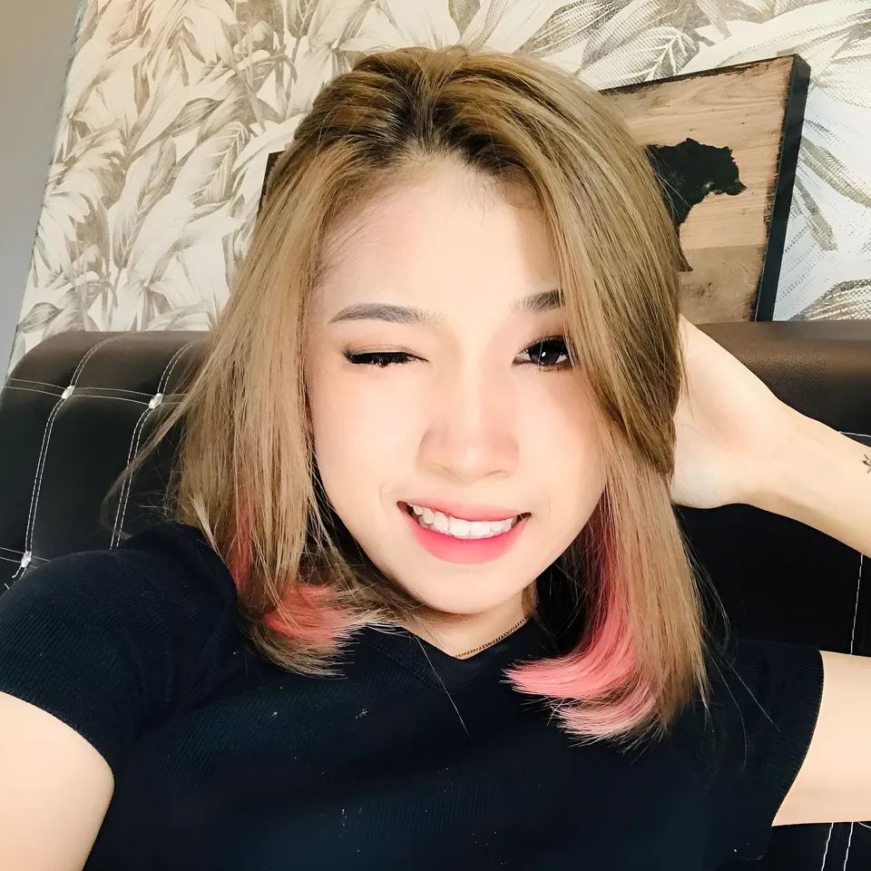Anis Jade Bennett with pink-tipped hair smiling while seated on a couch