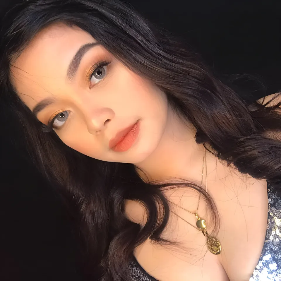 Ann Burdeos with dark hair and gold necklace in close-up portrait
