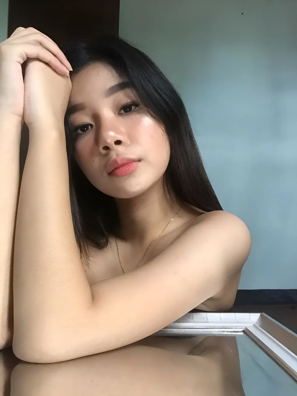 Ariane Quevedo with dark hair and necklace resting arm on reflective surface