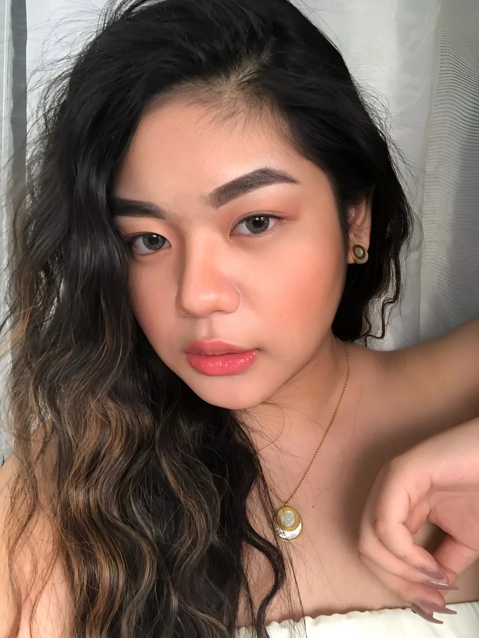 Ayca Delos Santos with long dark hair and necklace in close-up portrait
