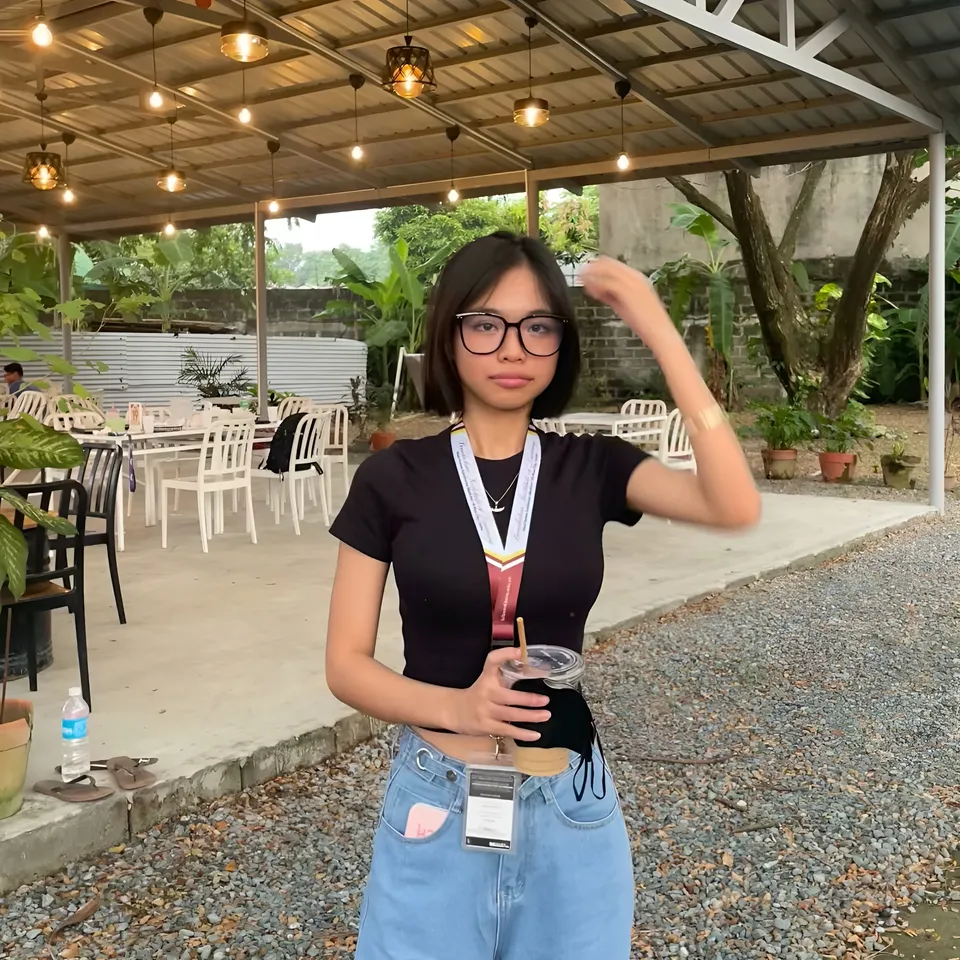 Beri Sinclair in black top and jeans holding drink outdoors