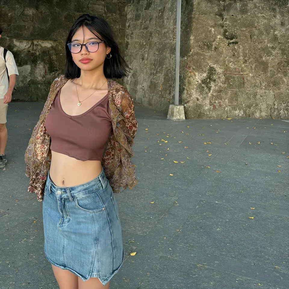 Beri Sinclair wearing brown crop top and denim skirt standing outdoors