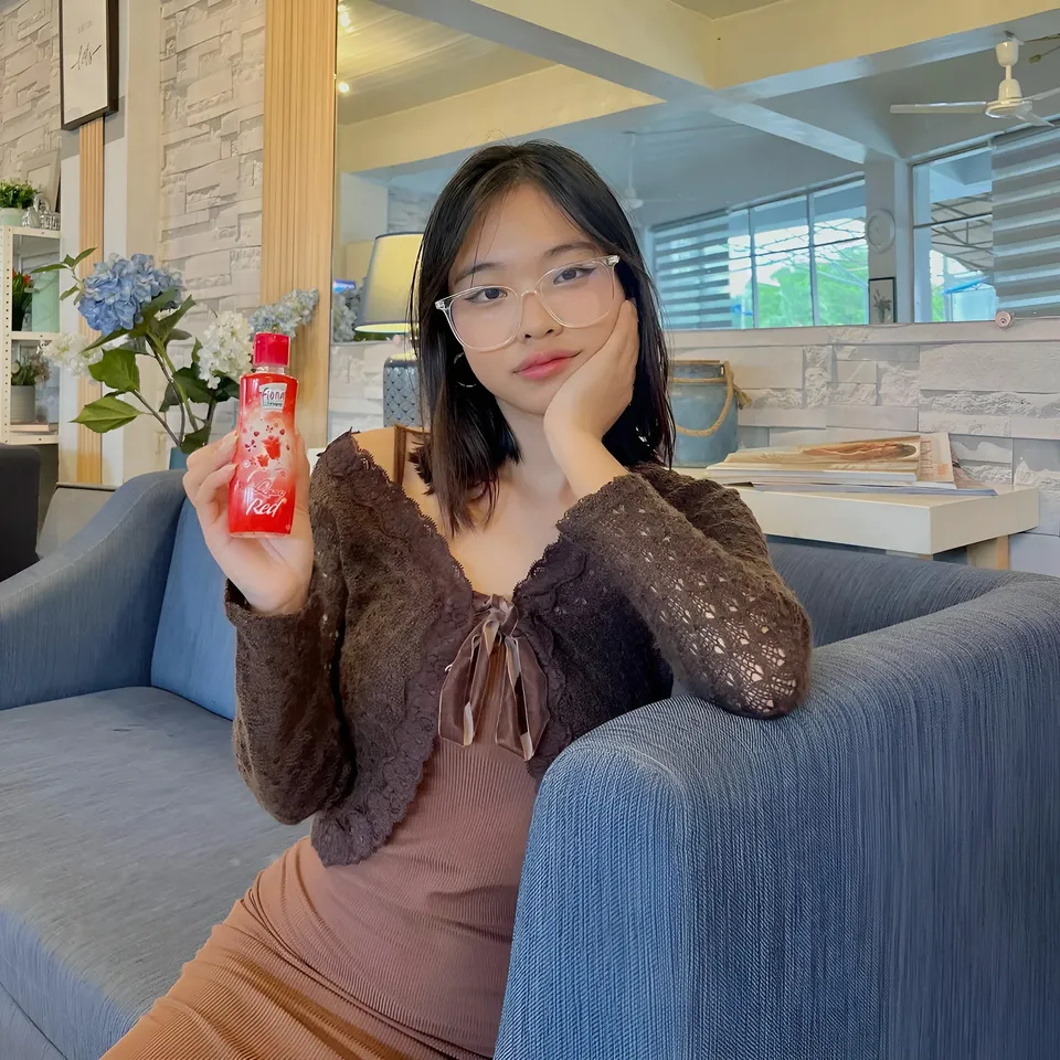 Beri Sinclair holding red bottle while seated on blue couch