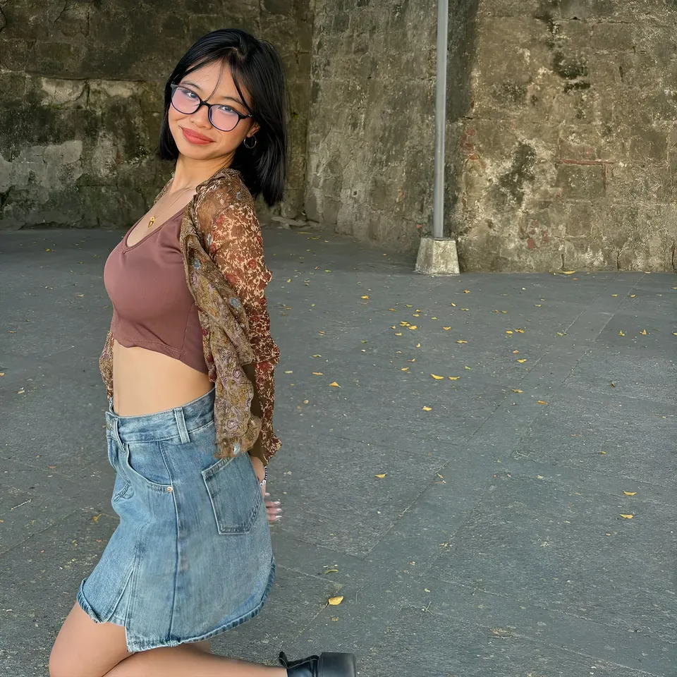 Beri Sinclair wearing glasses and layered clothing, kneeling outdoors