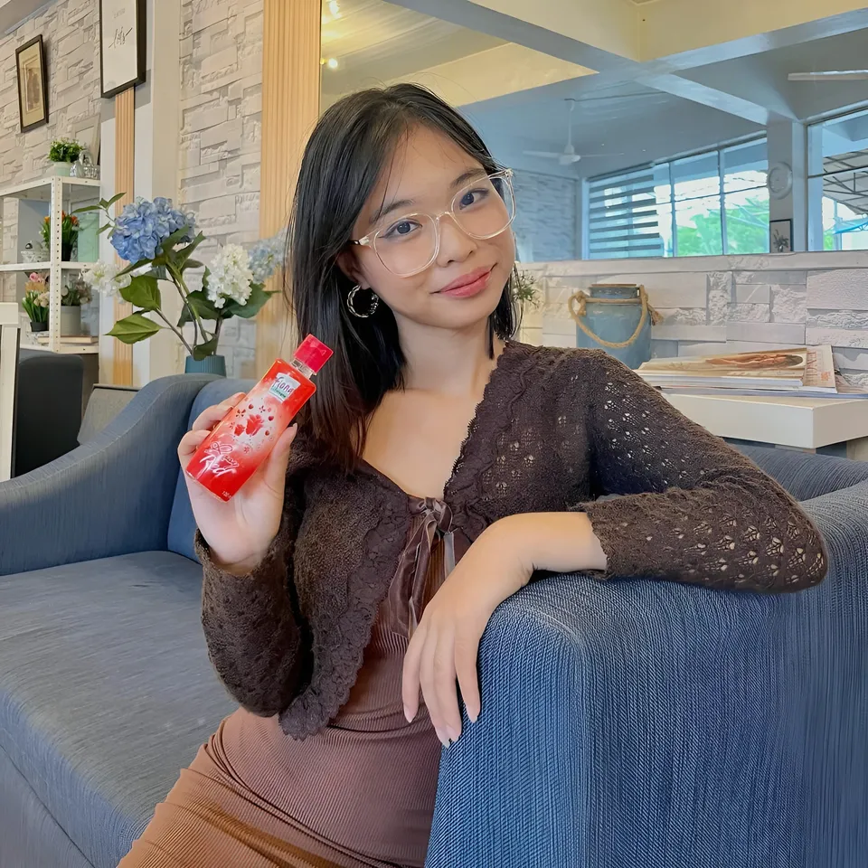 Beri Sinclair holding red bottle while seated on blue couch