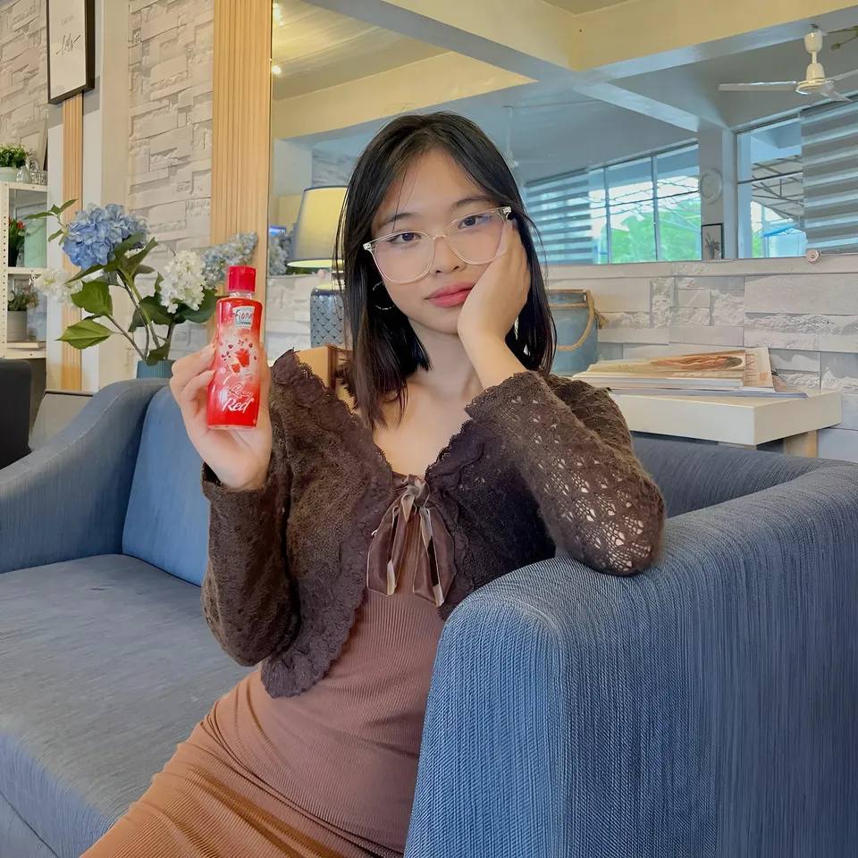 Beri Sinclair holding red bottle while seated on blue couch