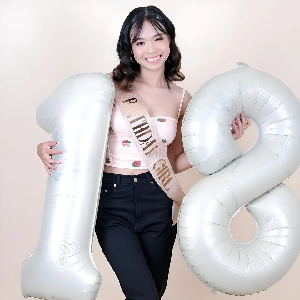 Beri Sinclair holding large silver number one and eight balloons