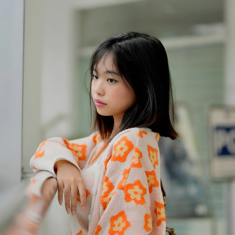 Beri Sinclair in orange floral cardigan leaning against surface