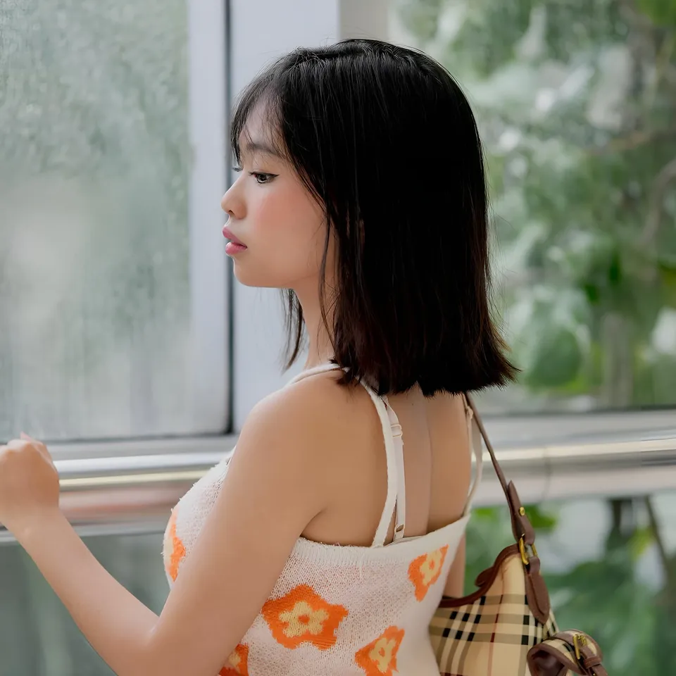 Beri Sinclair in white top with orange flowers, holding shoulder bag