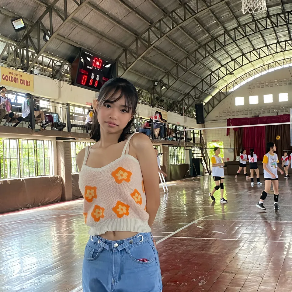Beri Sinclair in patterned top stands in gymnasium with volleyball players