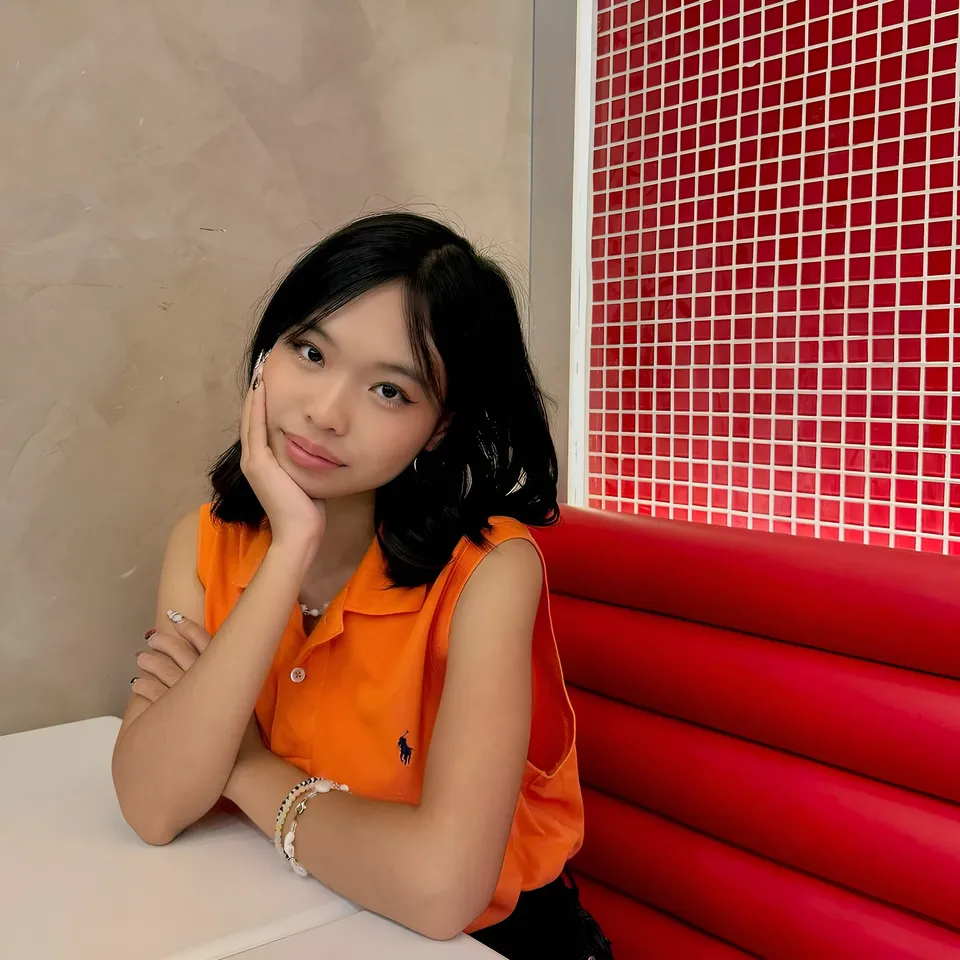 Beri Sinclair in orange top seated at table with red booth