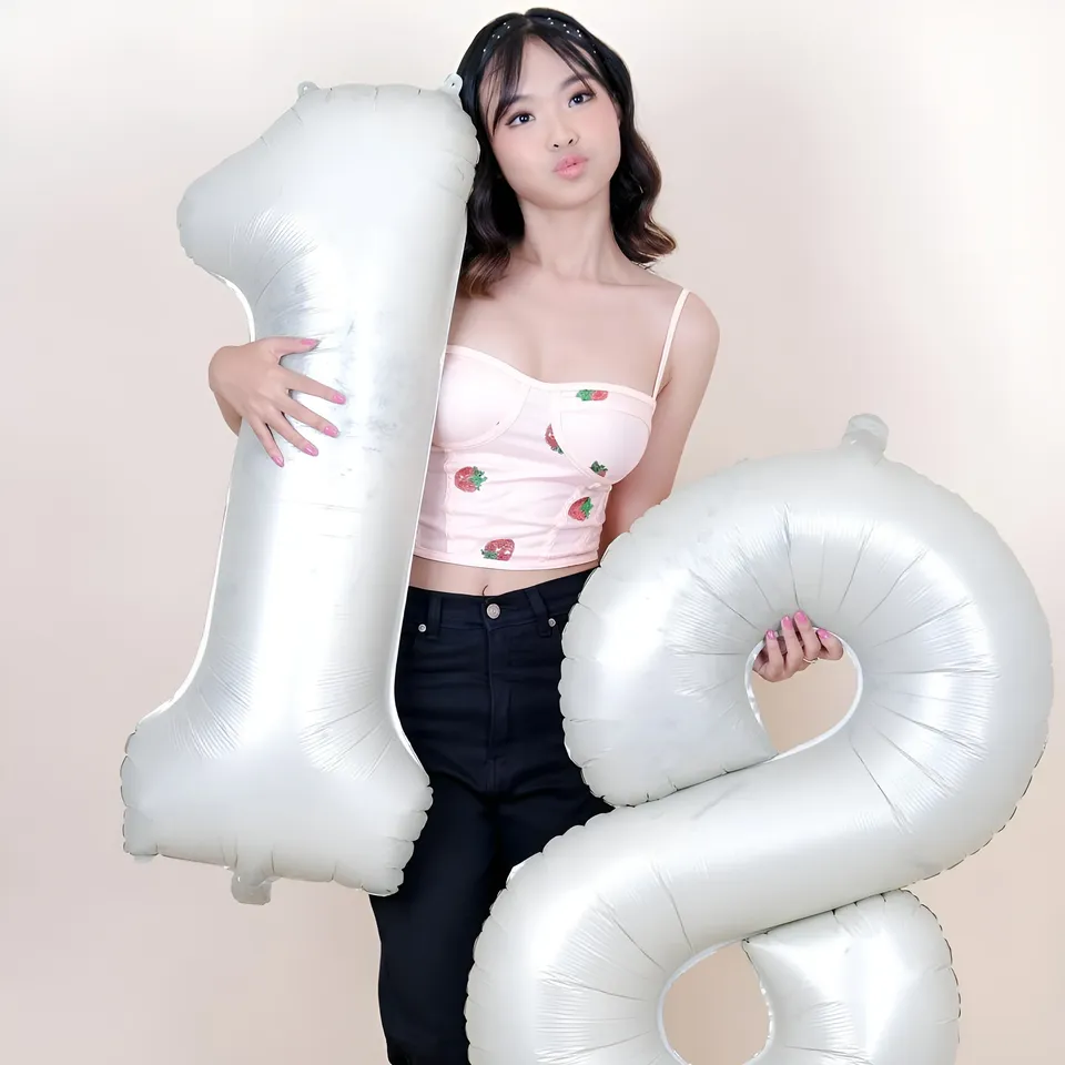 Beri Sinclair holding large silver number one and two balloons