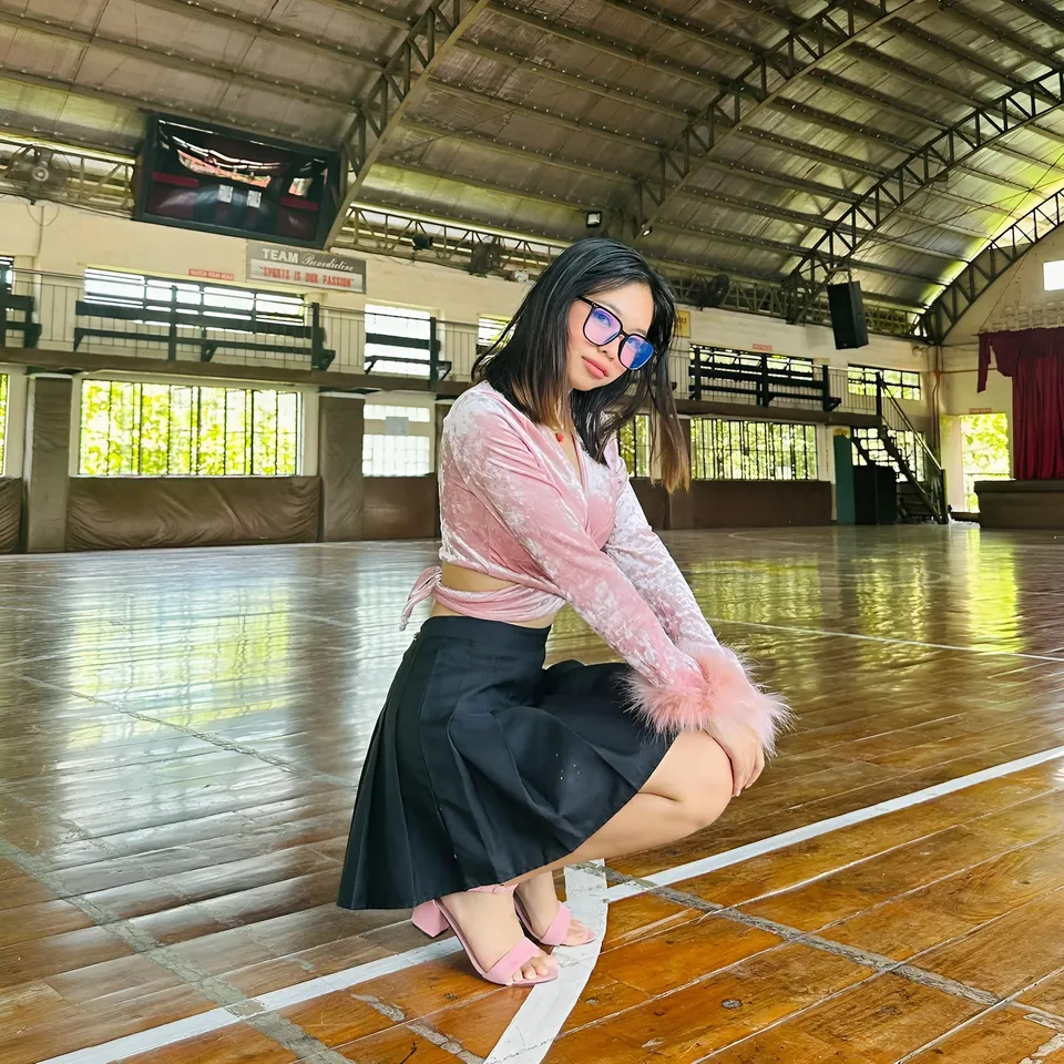 Beri Sinclair in pink top and black skirt crouching in gymnasium