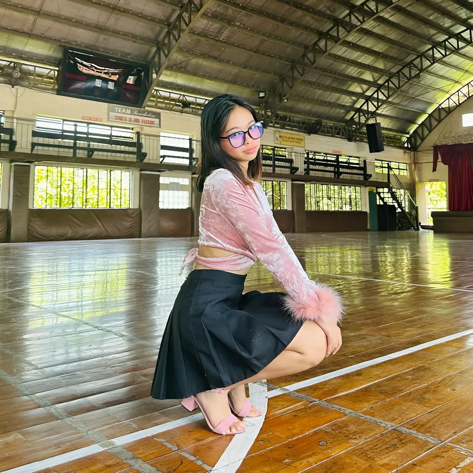 Beri Sinclair in pink top and black skirt crouching in gymnasium