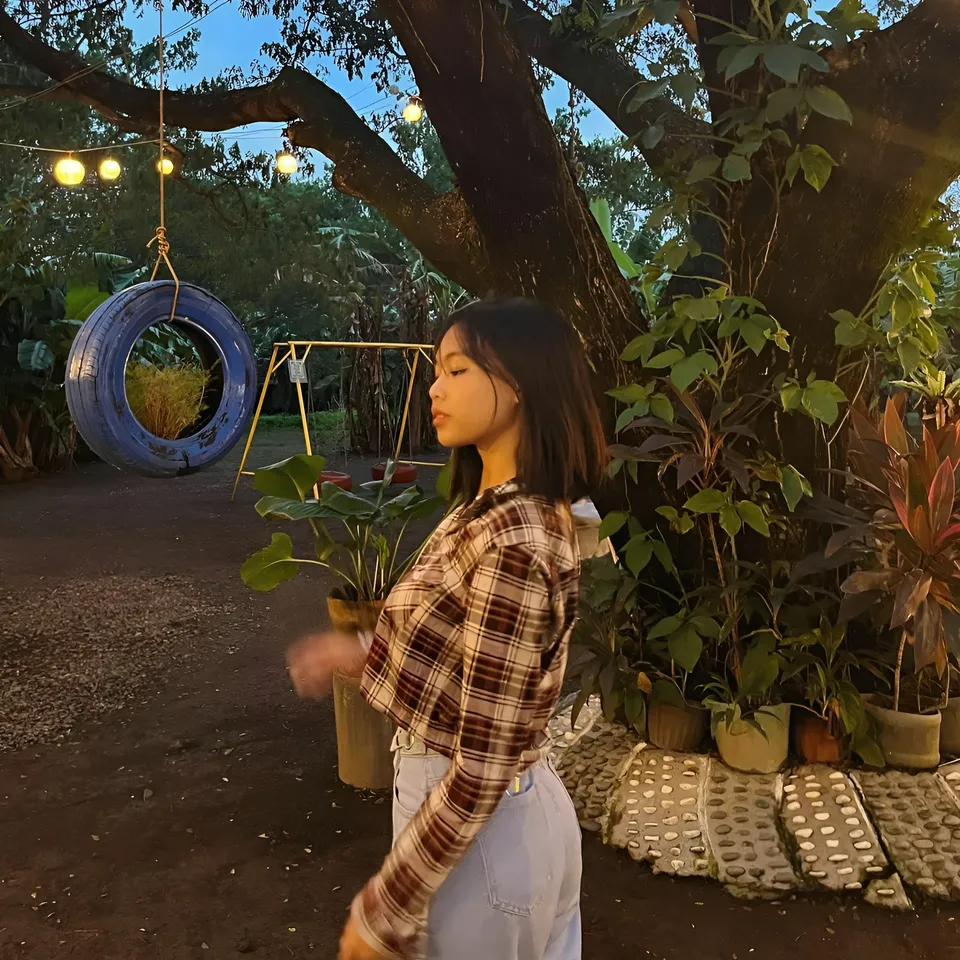 Beri Sinclair in plaid shirt stands near tree with hanging tire swing