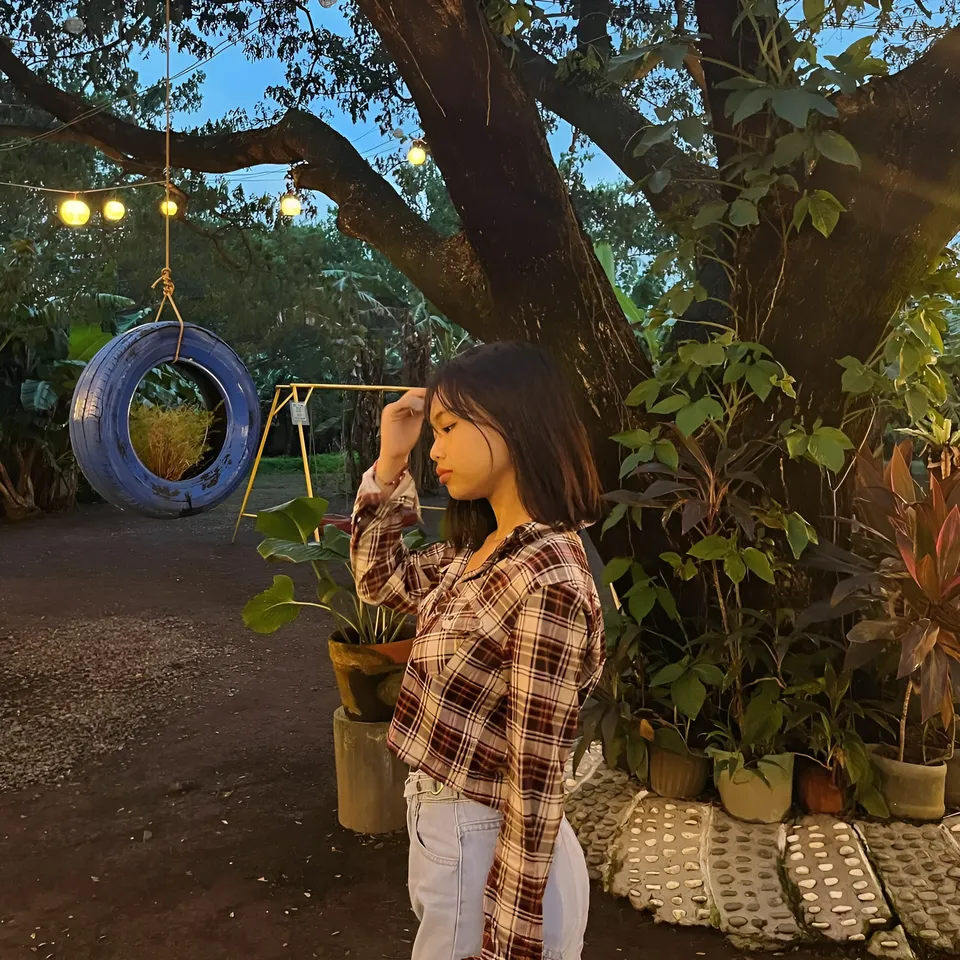 Beri Sinclair in plaid shirt stands near tree with hanging tire swing