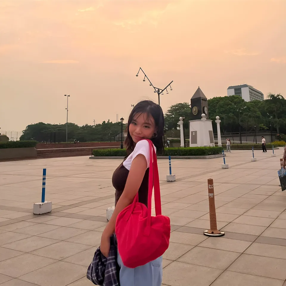 Beri Sinclair smiling over shoulder with red bag in public square