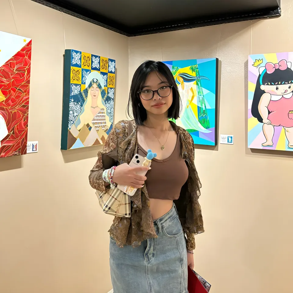 Beri Sinclair holding phone and bag in art gallery with colorful paintings