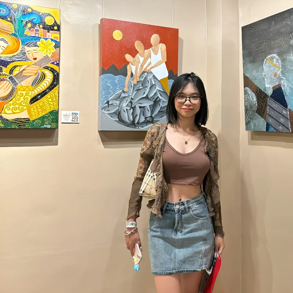 Beri Sinclair standing in art gallery with three paintings behind her