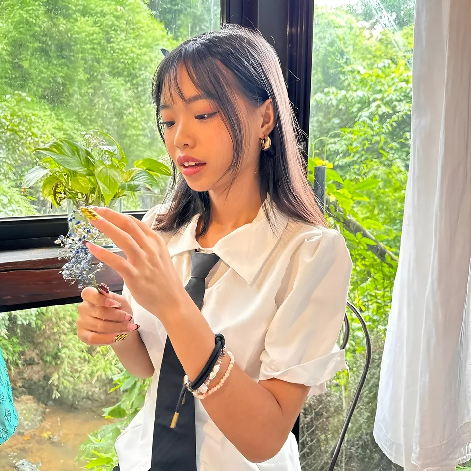 Beri Sinclair in white shirt holding small flower arrangement indoors