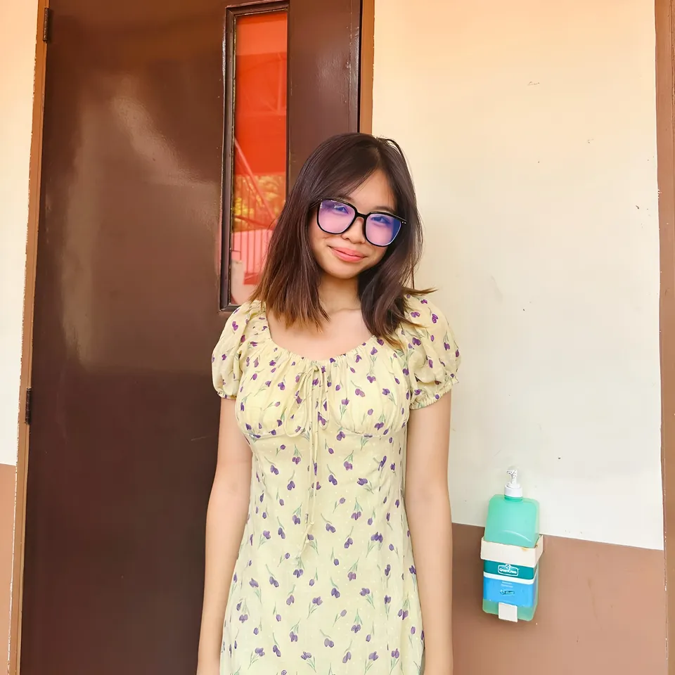 Beri Sinclair in yellow floral dress standing near door