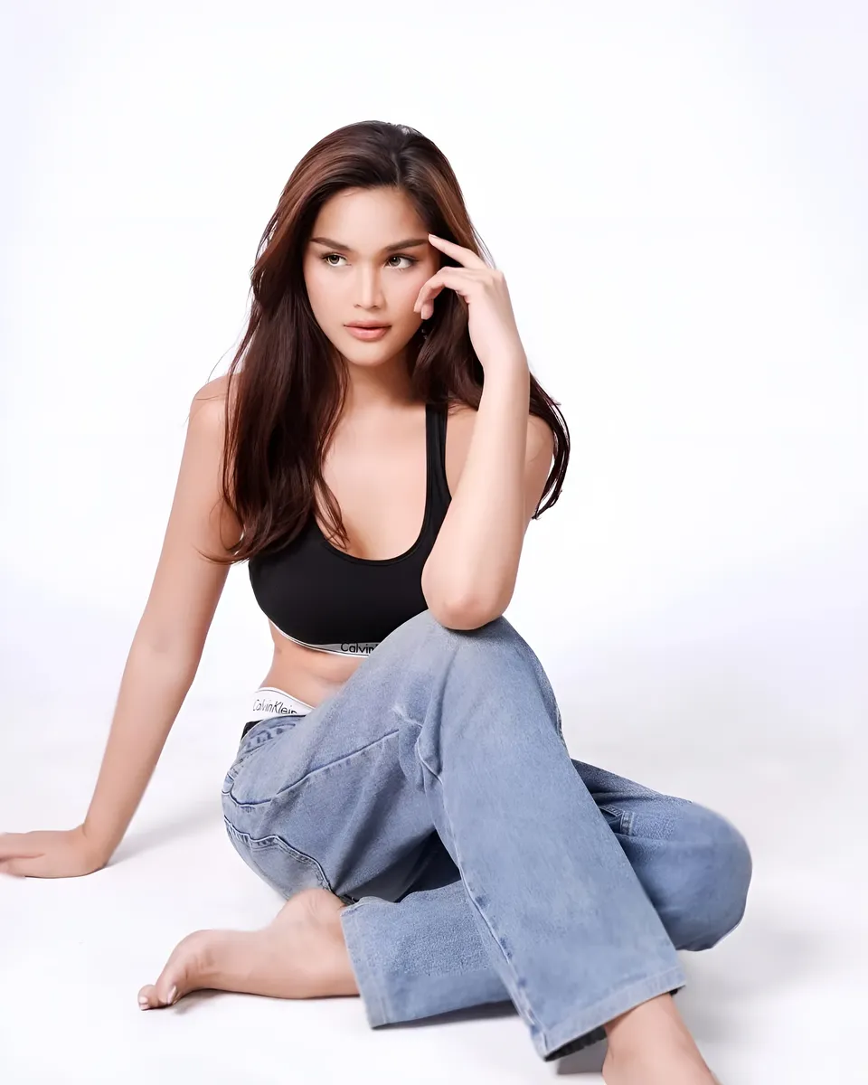 Brey Marti wearing black top and jeans sitting on floor