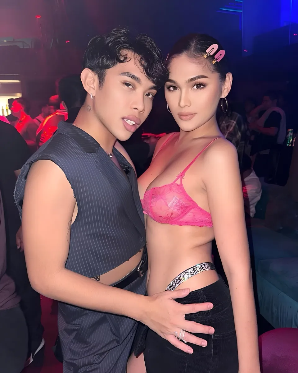 Brey Marti — Two people pose closely together in a dimly lit club setting