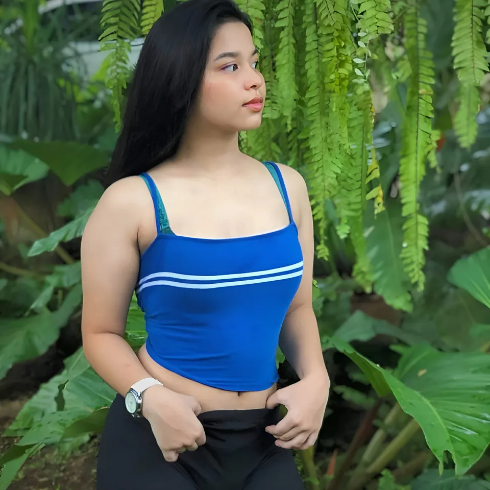 Callista Ray in blue top with white stripes standing in green foliage