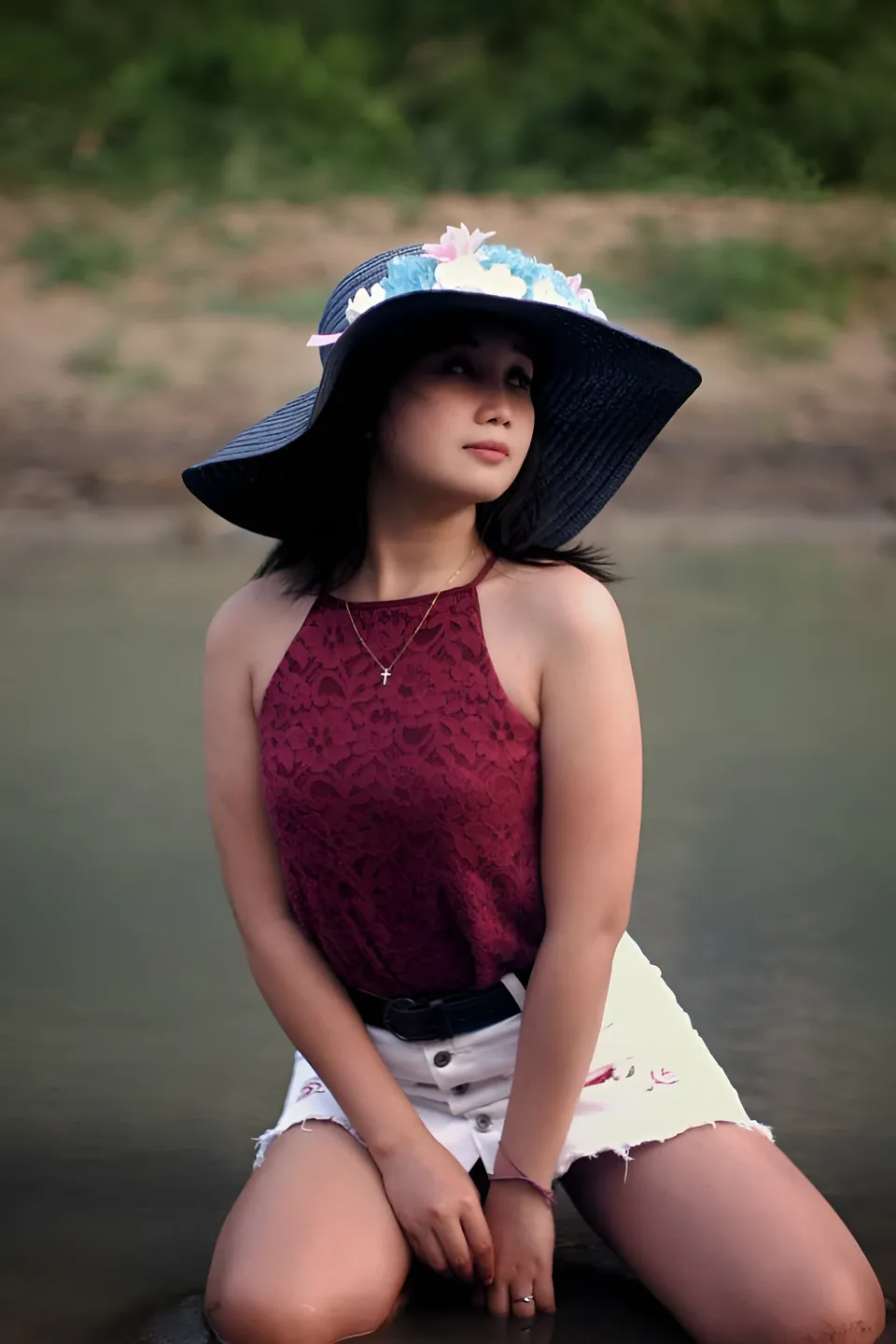 Camille Miguel Asuten wearing hat and top seated by water