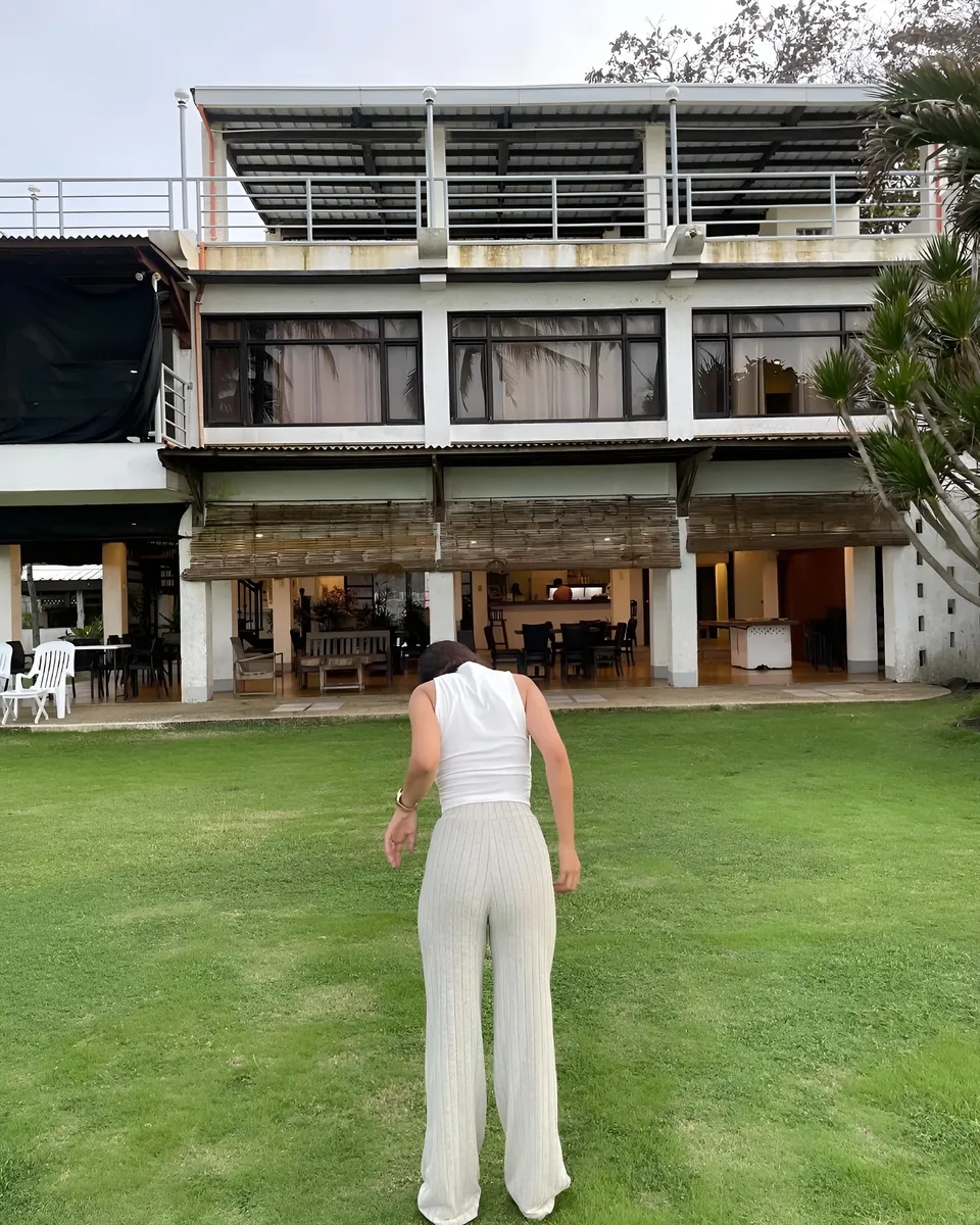 Cassidy Rowan in white top and pants stands on grass in front of building