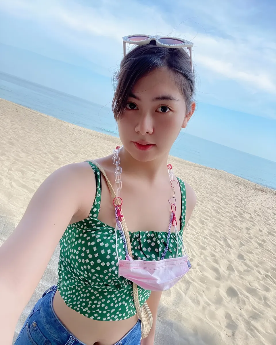 Cathy Holy in green floral top on sandy beach with ocean background