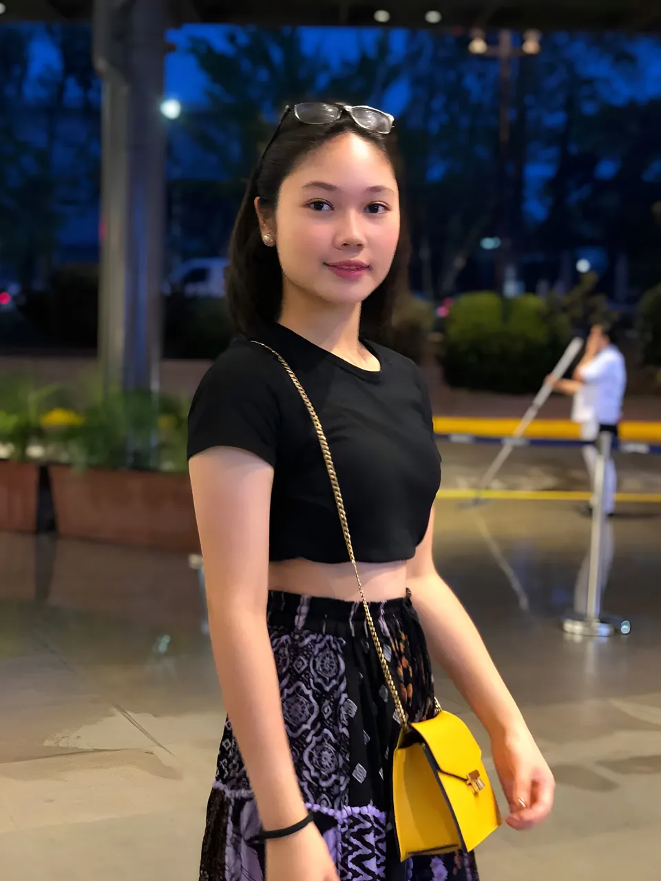 Chelle Avery in black top and patterned skirt stands outdoors at dusk