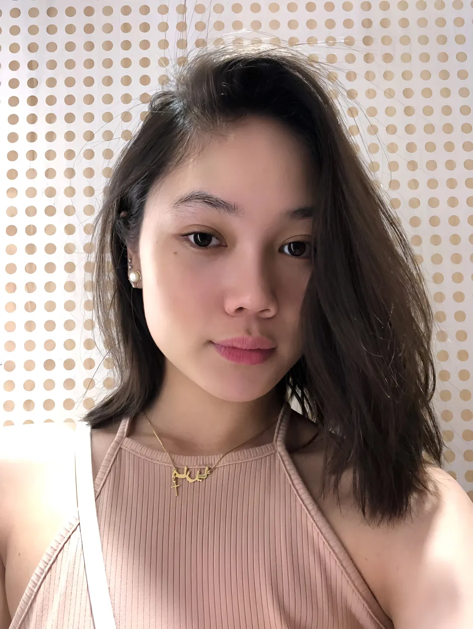Chelle Avery in pink top with gold necklace and pearl earrings