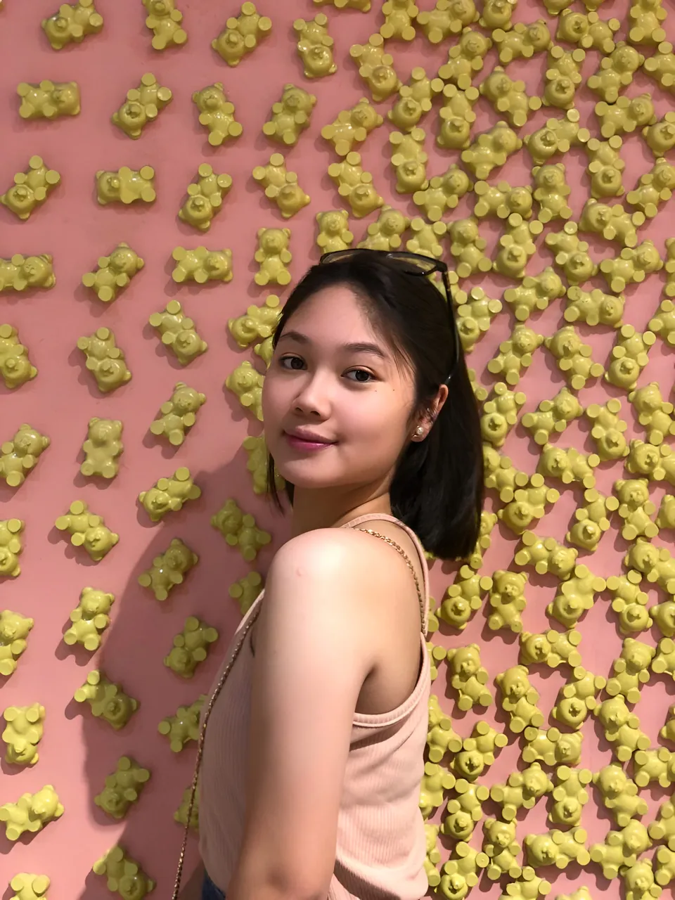 Chelle Avery in pink top poses against yellow bear wall