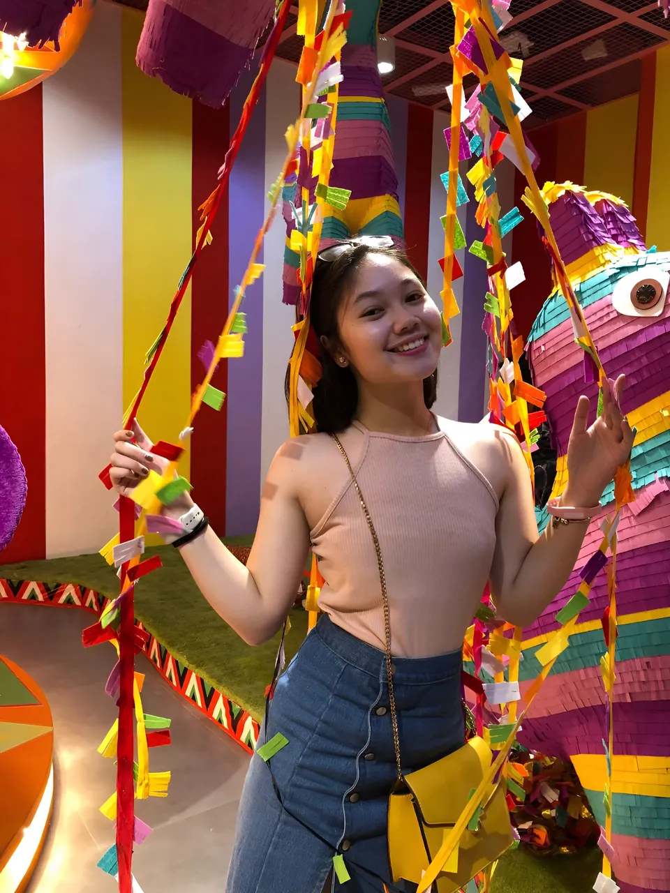 Chelle Avery in pink top stands near colorful piñatas