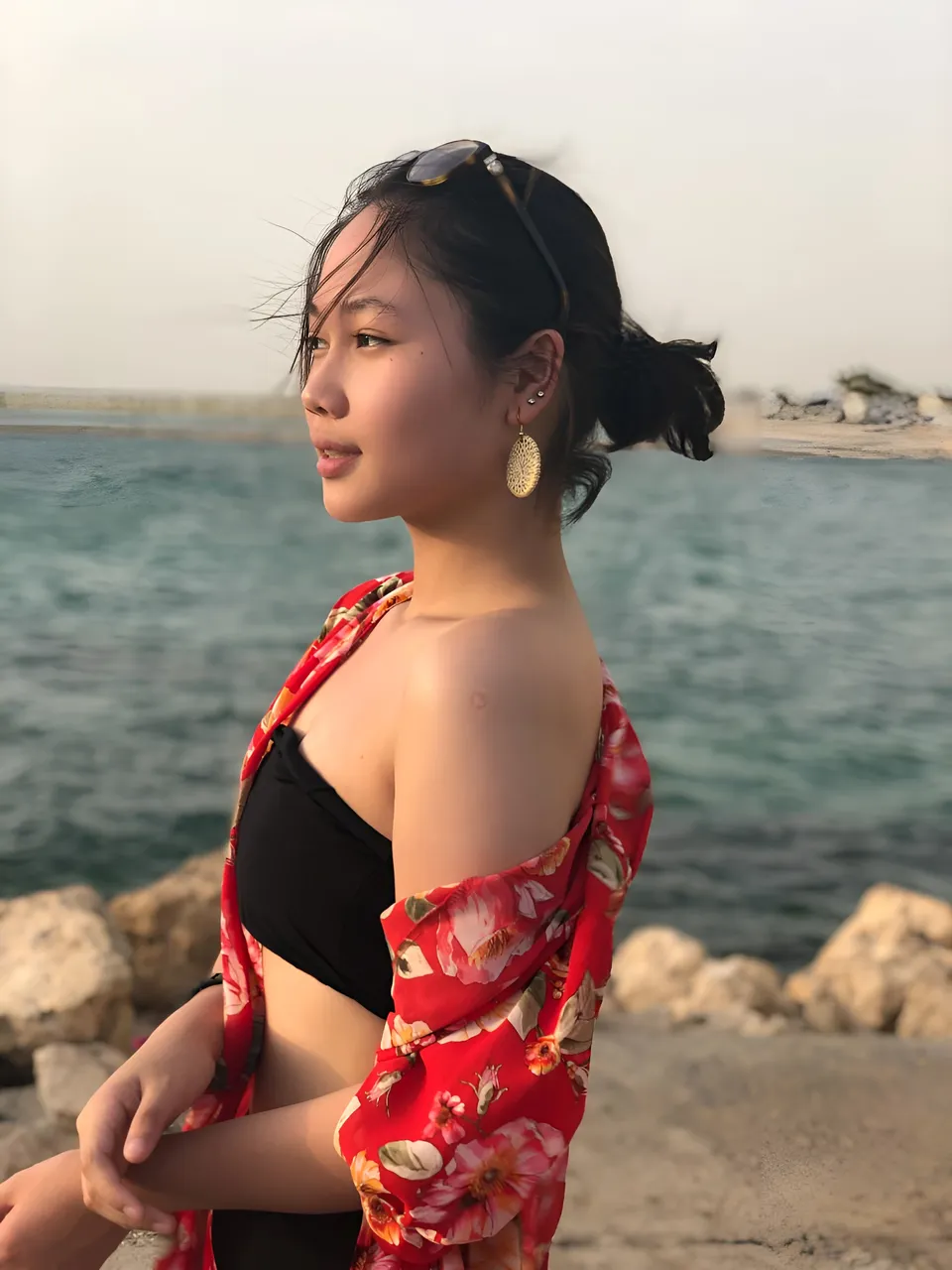 Chelle Avery in red floral top and black top near water