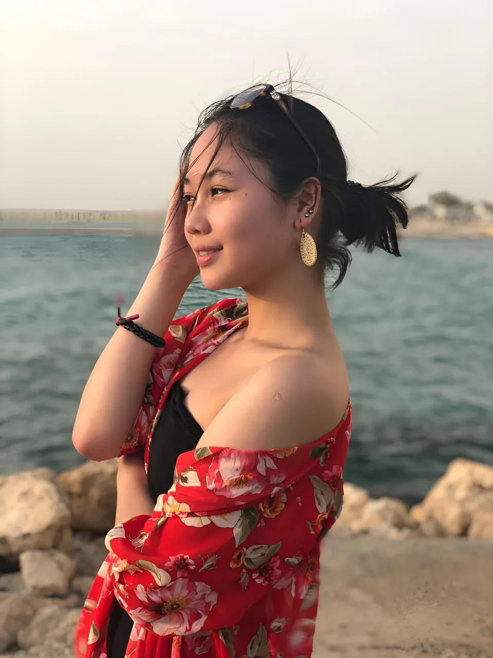 Chelle Avery in red floral top standing by water