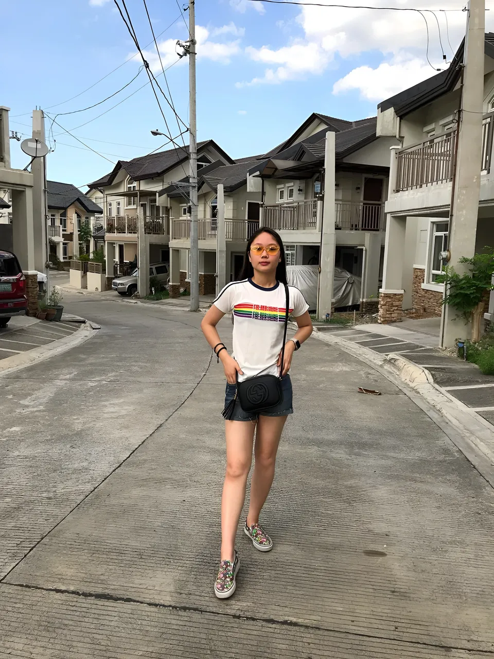 Chelle Avery wearing a white shirt and black shorts stands on a residential street