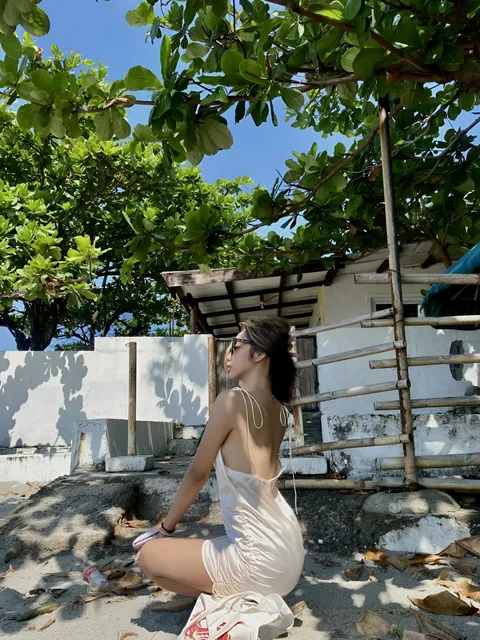 Czarina Blake in white dress sitting under tree outdoors