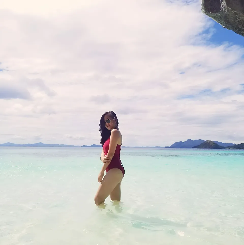 Diedre Anne in red swimsuit standing in shallow ocean water