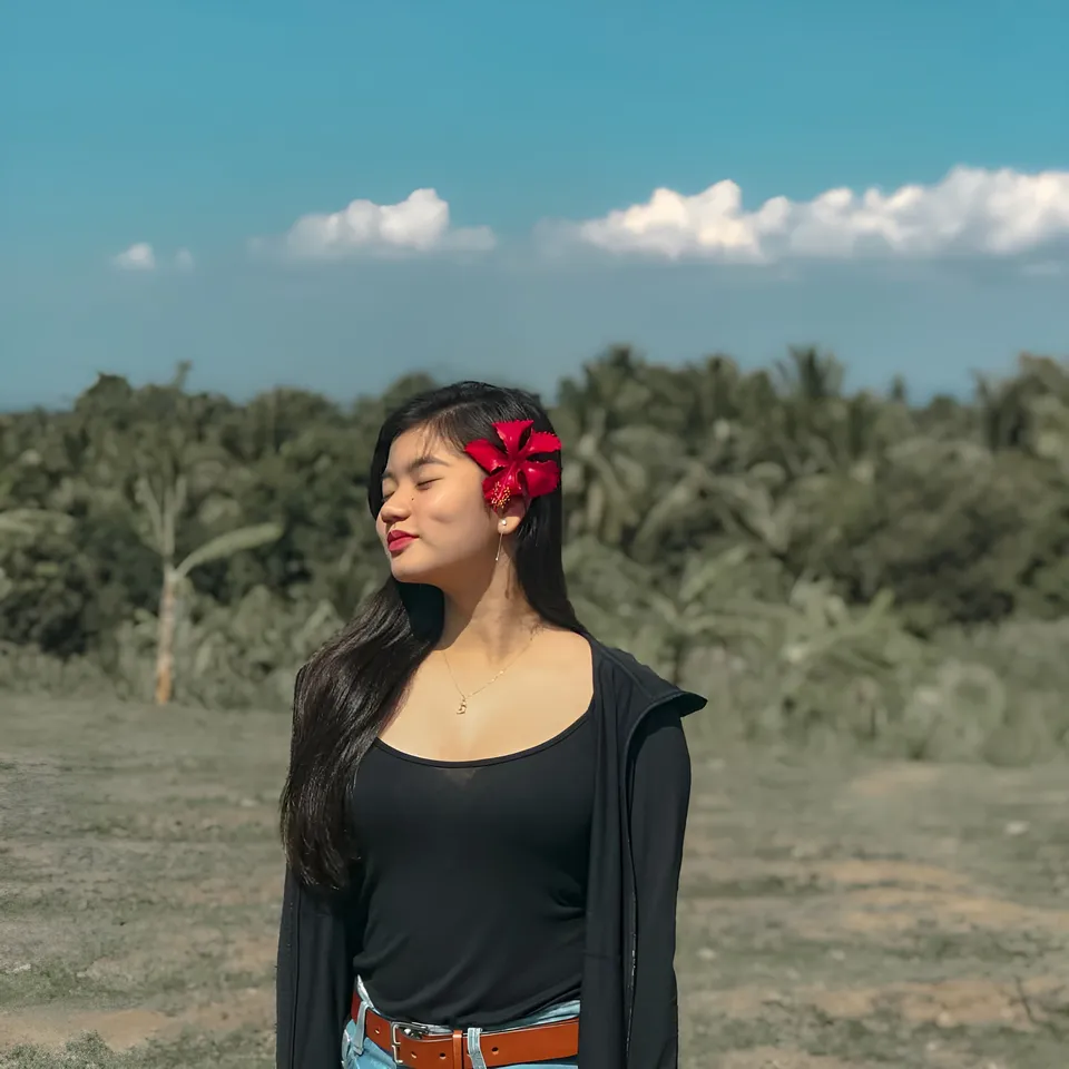 Ellidiethe Rielle with red flower in hair, standing outdoors in field